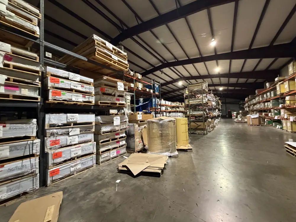The aisle of a plastics distributor warehouse, stacked with pallets of sheet